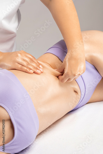 The masseur makes a massage on the abdomen  waist and hips in the spa. Overweight treatment  body sculpture. The concept of cosmetology and massage.