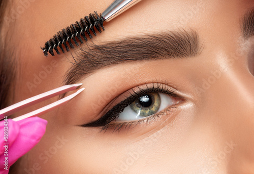 Makeup artist plucks eyebrows. Long-lasting styling of the eyebrows and color the eyebrows. Eyebrow lamination. Professional make-up and face care. photo