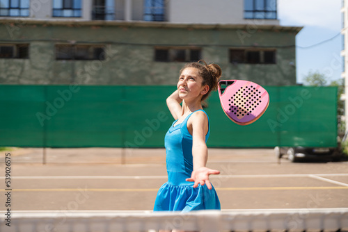 Sportive young girl with racquet playing padel in the open court outdoors © diignat