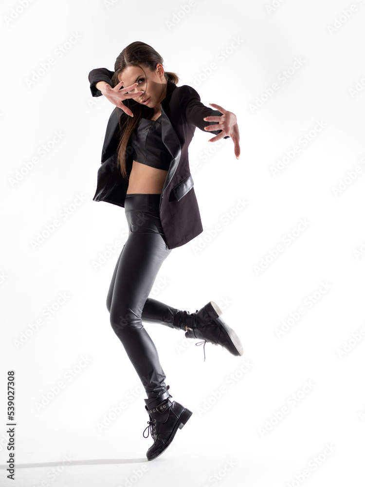 Stylish young woman in a black hat and jacket, dancing in the studio on a white background Stylish young woman in a black hat and jacket, dancing in the studio on a white background