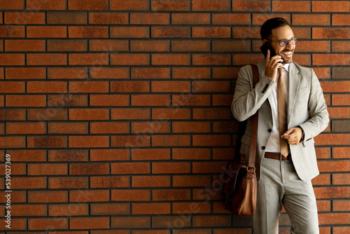 Business man walking out of his apartmant Business man in suit Red bricks wall
 photo