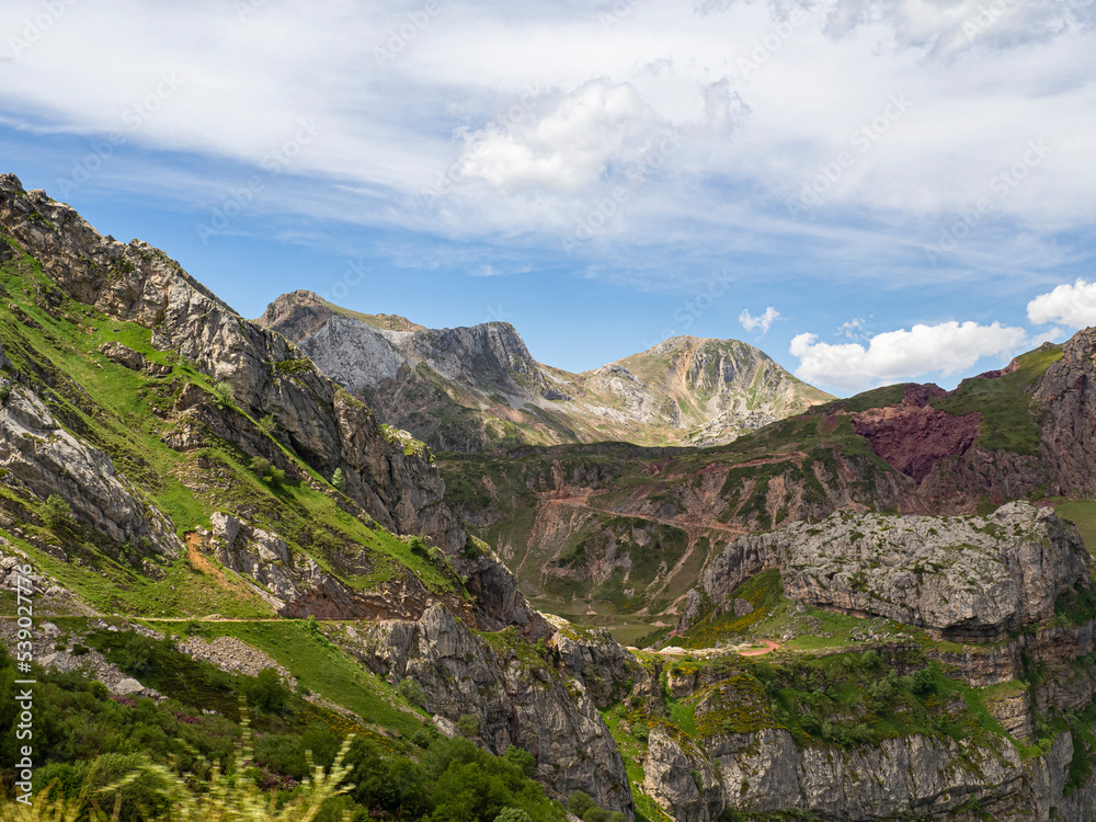 Montañas singulares en el paisaje de Somiedo en Asturias, llenas de vegetación con flores de colores morados, un cielo azul con nubes blancas en verano de 2021, España.