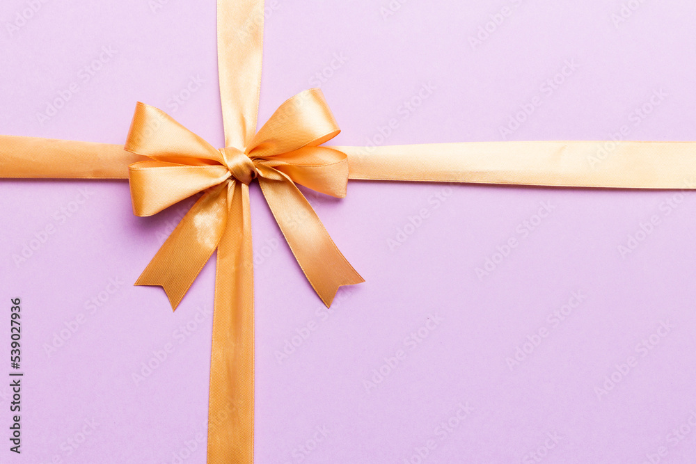 Top view of gold ribbon rolled and yellowbow isolated on colored background. Flat lay with copy space Top view of gold ribbon rolled and yellowbow isolated on colored background. Flat lay with copy space
