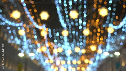 Illumination of the street on Christmas, a lot of lights of yellow blue green colors, the effect of blurring the lights