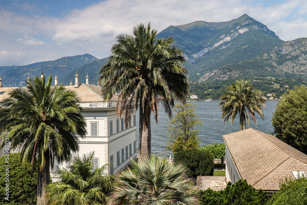 Villa Menzi with Palm Tree in Bellagio. Beautiful View of Italian Architecture with Lake Como and Hilly Mountain in Botanical Garden during Summer Day.