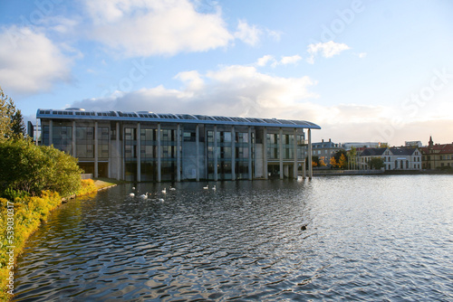 Reykjavik City Hall (Ráðhús Reykjavíkur in Icelandic) over Lake Tjornin on a sunny day with a cloudy blue sky.  Image has copy space. photo