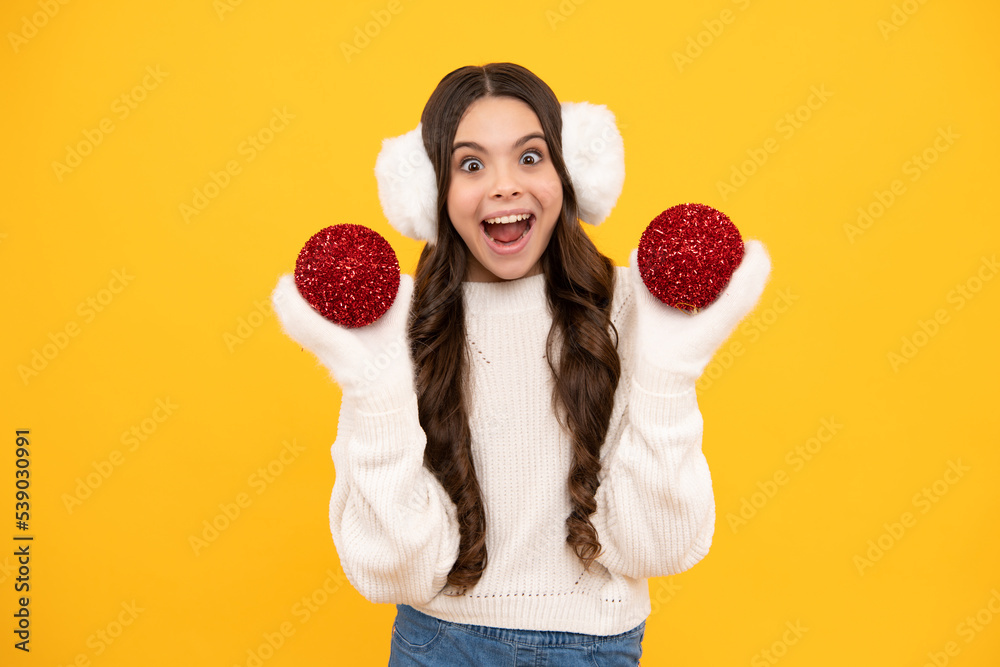 Portrait of funny teenage girl in winter weather dressed in warm clothes and knitted gloves play with christmas ball. Portrait of funny teenage girl in winter weather dressed in warm clothes and knitted gloves play with christmas ball.