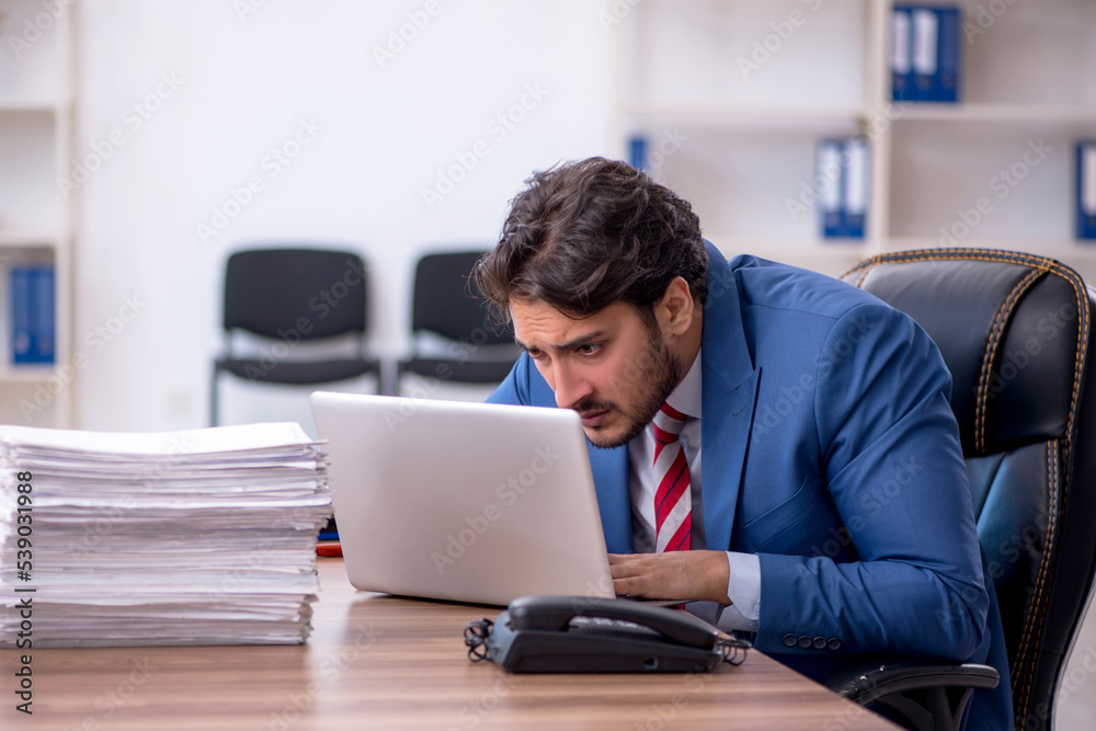 Young male employee and too much work in the office Young male employee and too much work in the office