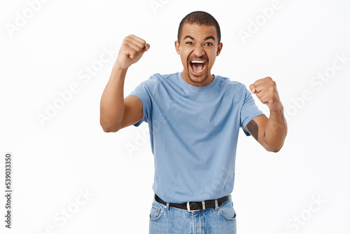 Enthusiastic arab guy shouting, cheering, watching sports game and rooting for team, standing over white background