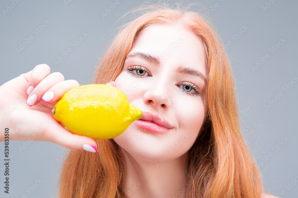 Young beautiful woman eating lemon isolated on gray background. Healthy eating concept. Diet. Young beautiful woman eating lemon isolated on gray background. Healthy eating concept. Diet.