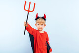 Cute little boy in devil halloween costume with horns and trident