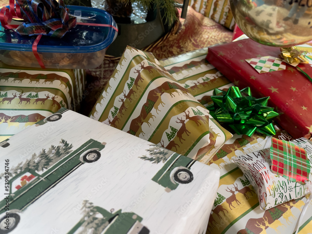 Fototapeta premium Wrapped Christmas presents with bows and tags stacked under the Christmas tree.