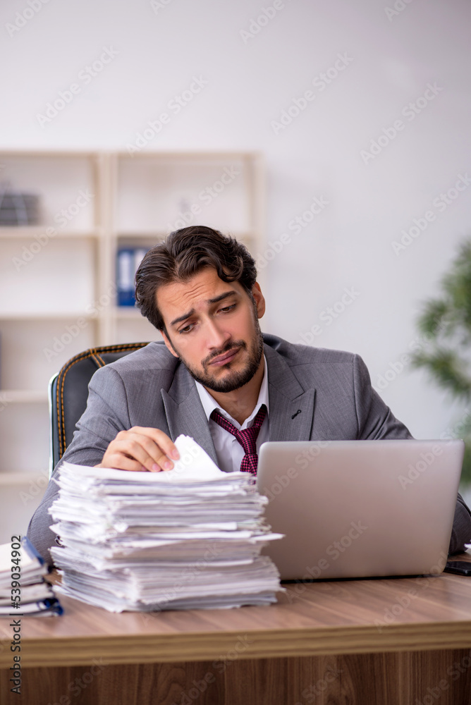 Naklejka premium Young male employee and too much work in the office