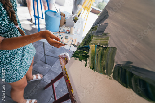 Close-up of woman's hand applying paint to a canvas