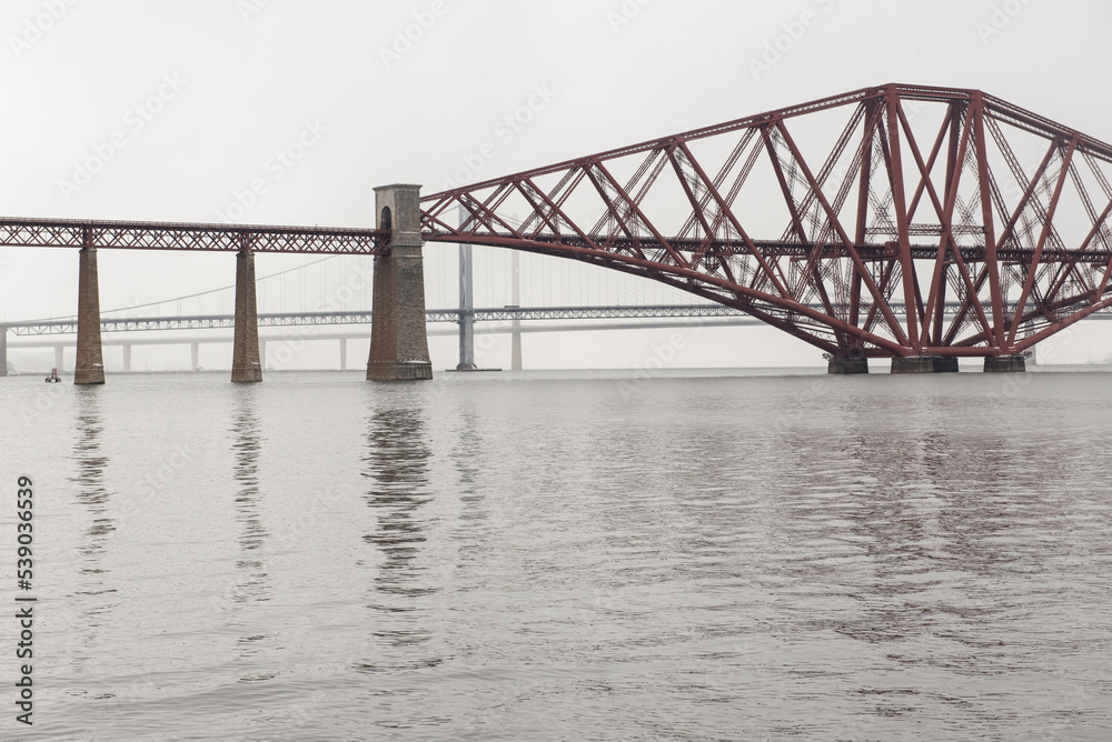 View of the George IV Bridge Rail Bridge from the distance across the water of the Firth of Forth in an overcast Winter day in Edinburgh, Scotland, UK, where the Queensferry Crossing and the Firth of 