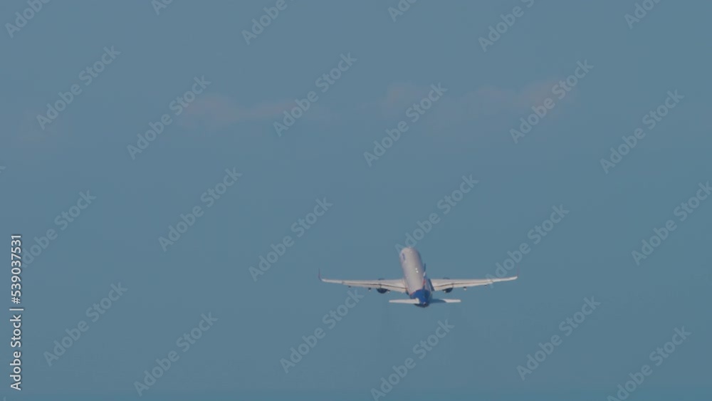 Passenger airliner climbing after takeoff in the blue sky. Rear view long shot, plane fly away Passenger airliner climbing after takeoff in the blue sky. Rear view long shot, plane fly away