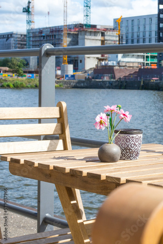 Sunny cozy seat at a wooden cafe table on the shore of Baakenhafen in Hamburg. View of the new Baakenpark in the Hafencity. photo