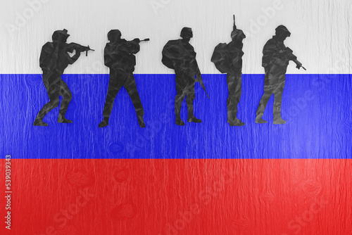 Photos Paper cutting of silhouettes of solders on a wooden table printed with the national flag of Russia