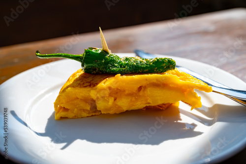 Typical snack in bars of Basque Country, pinchos or pinxtos, small slices of bread withn different toppings and fastened with skewers, San Sebastian, Spain. Potato tortilla with green pepper. photo