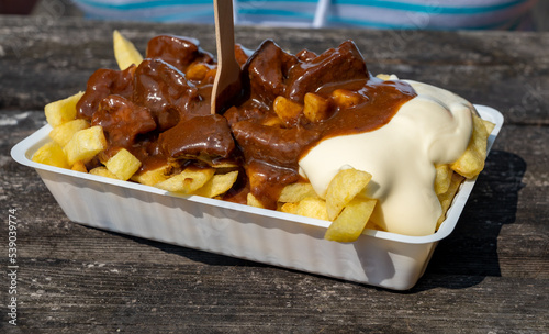 Lunch with traditional street food in Belgium, French fried potatoes with beef stew and mayonnaise photo