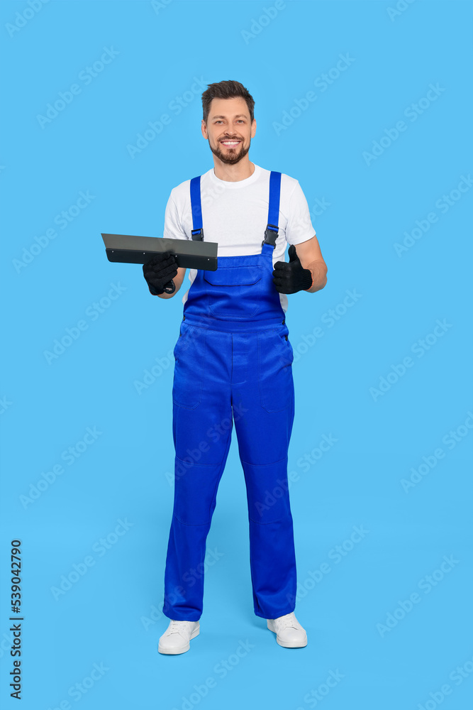 Professional worker with putty knife on light blue background Professional worker with putty knife on light blue background