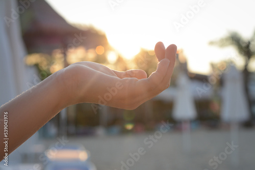 Girl holding her hand against sunlight on beach, closeup © New Africa