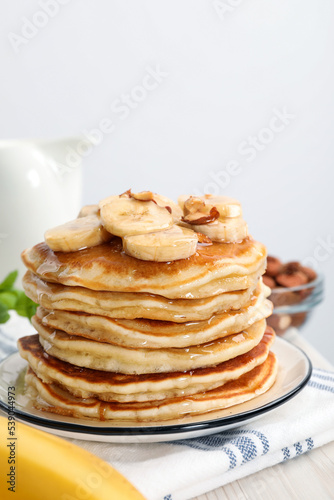 Tasty pancakes with sliced banana served on white wooden table, closeup. Space for text
