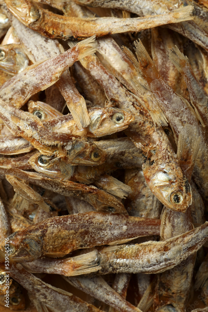 Many tasty dried anchovies as background, closeup