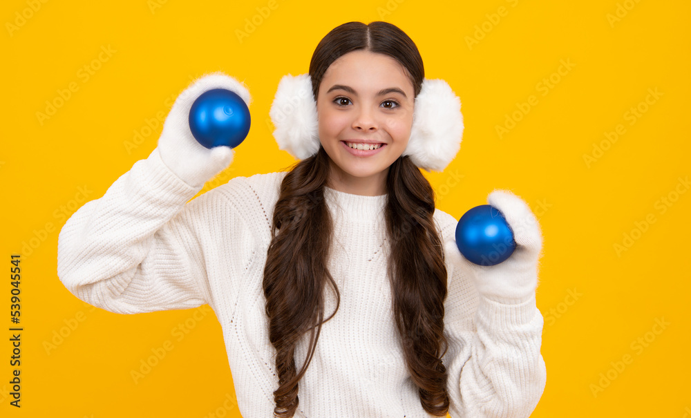 Portrait of teenager child girl wearing knitted gloves and winter sweater playing with christmas ball isolated on yellow studio background. Happy face, positive and smiling emotions. Portrait of teenager child girl wearing knitted gloves and winter sweater playing with christmas ball isolated on yellow studio background. Happy face, positive and smiling emotions.