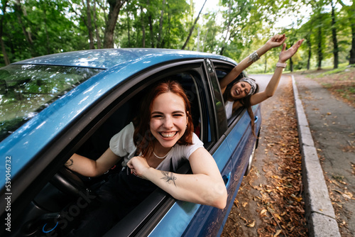 Two girlfriends fool around and laughing together in a car