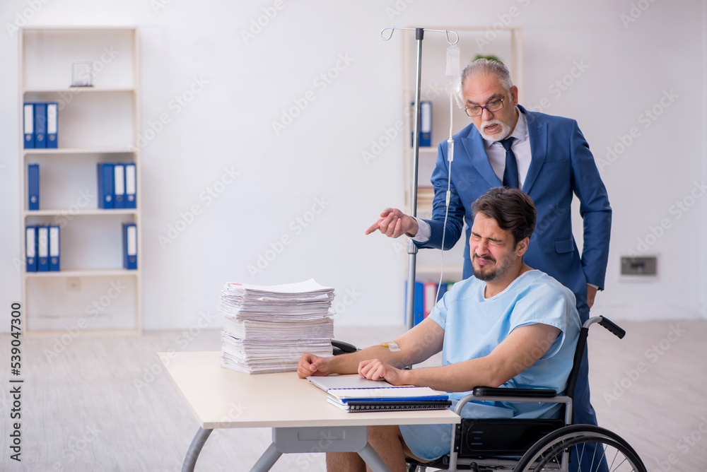 Young male employee in wheel-chair feeling bad at workplace