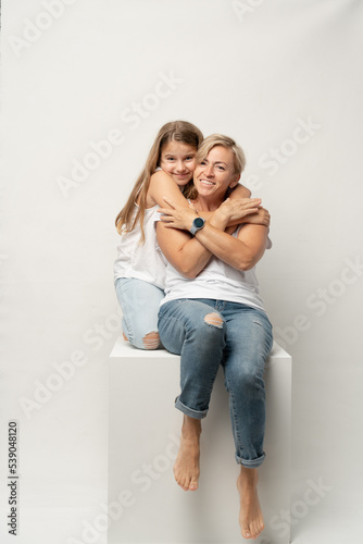 Cute girl hugging her middle age mother in white background, smiling.