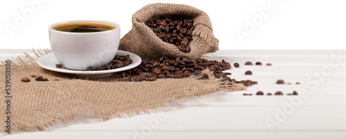 Cup of hot coffee with beans on background