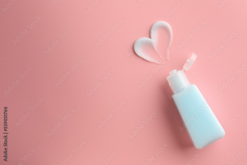 Tube and sample of facial cream on pink background, top view. Space for text