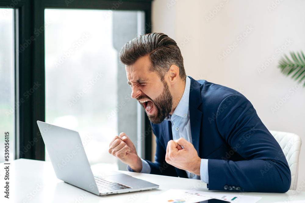 Angry annoyed frustrated caucasian business man, sitting at workplace with laptop, screaming, gesturing with fists, failed deal, disappointed with project result, experiencing negative emotions Angry annoyed frustrated caucasian business man, sitting at workplace with laptop, screaming, gesturing with fists, failed deal, disappointed with project result, experiencing negative emotions