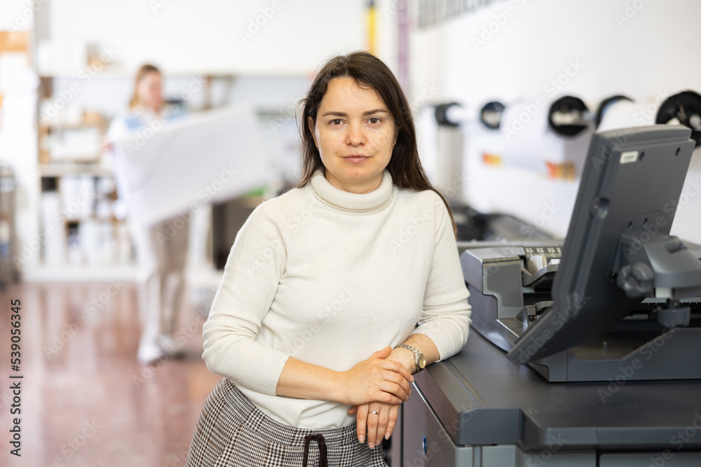 Technician female operator calibrating plotter machine, typing on computer keyboard