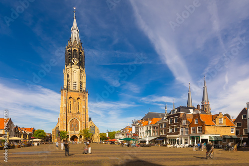 Scenic view of historical central Cameretten square of Dutch city of Delft with peculiar typical townhouses, busy street cafes and Gothic belfry of medieval Protestant church Nieuwe Kerk on summer day