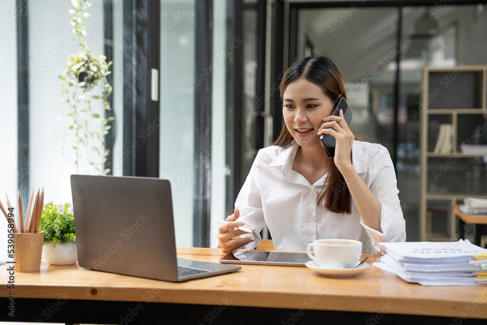 Asian Businesswoman Using laptop computer and working at office with calculator document on desk, doing planning analyzing the financial report, business plan investment, finance analysis concept. Asian Businesswoman Using laptop computer and working at office with calculator document on desk, doing planning analyzing the financial report, business plan investment, finance analysis concept.