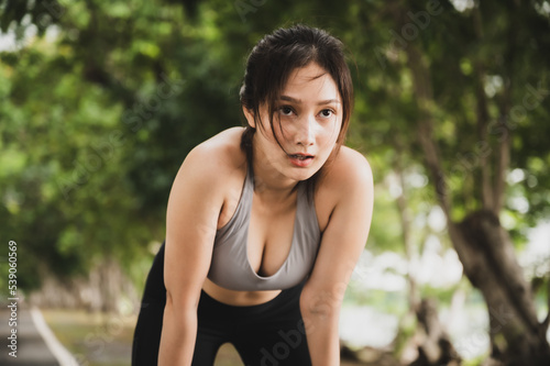 Asian woman wearing sportswear and tired engaged in fitness in public park. Her gaze was determined to lose weight. Healthy lifestyle activity concept