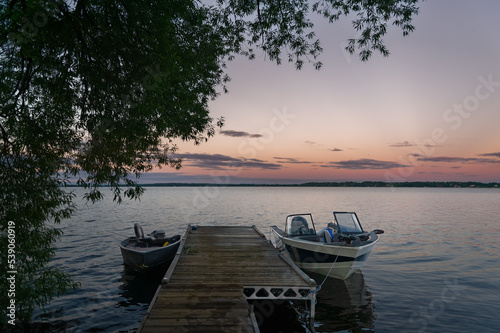 Fishing boats tied on a wooden dock in the Bay of Quinte at sunset 