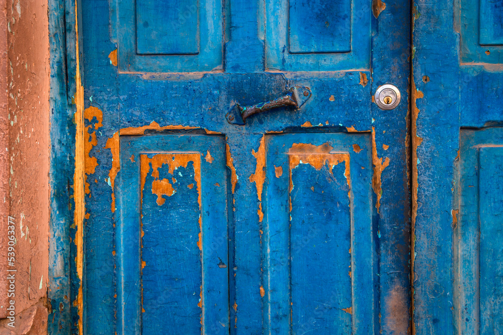 Old wooden blue painted and textured door, with rusty metal hinge Old wooden blue painted and textured door, with rusty metal hinge