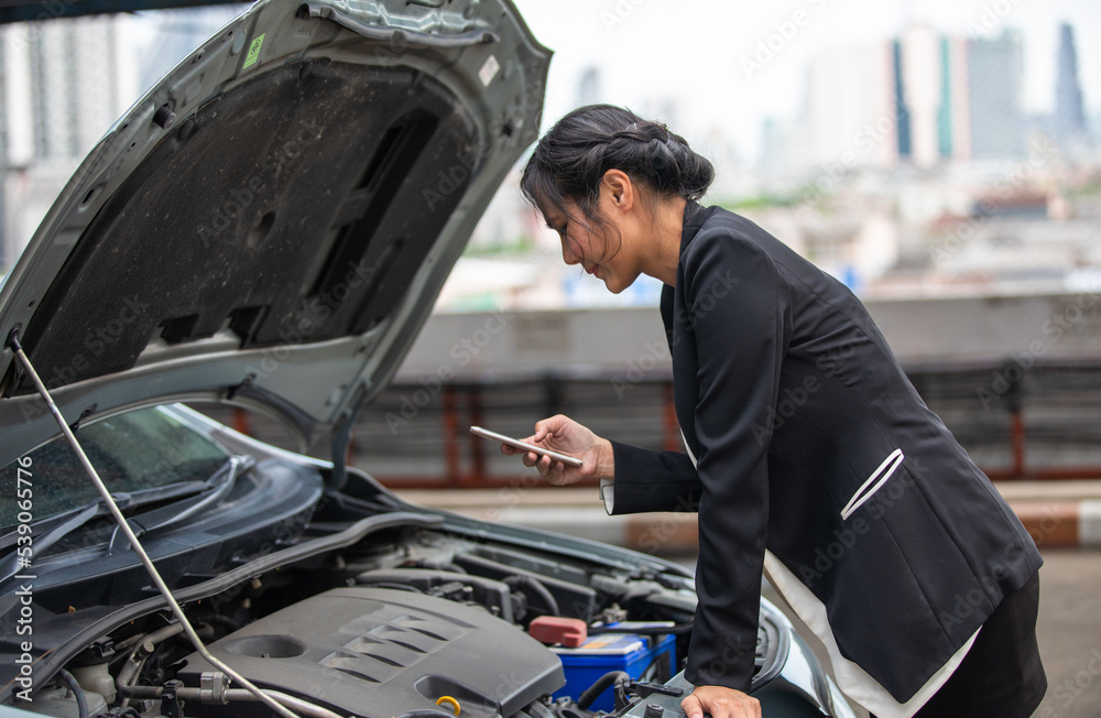 A businesswoman is calling for help as her car breaks down on the side of the road. A businesswoman is calling for help as her car breaks down on the side of the road.