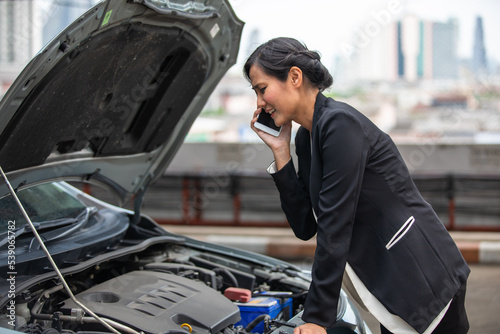 A businesswoman is calling for help as her car breaks down on the side of the road.