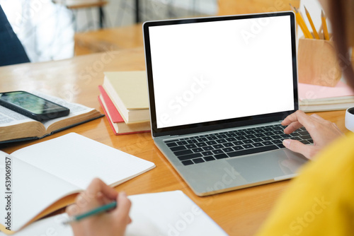 Close up of woman studying online using laptop with blank screen.