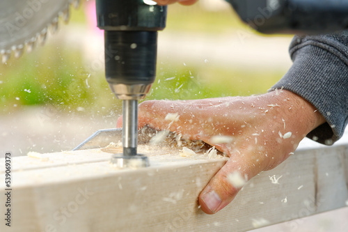 Carpenter builder working overall equals a wooden bar with a milling machine in the workshop.