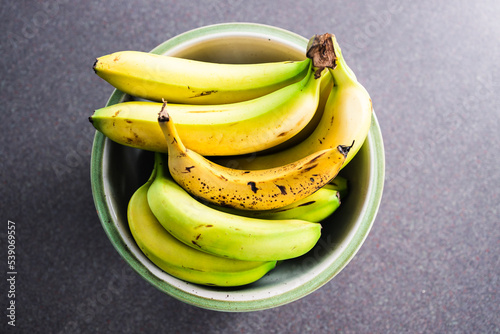 fruit bowl with bunches of bananas with only one being ripe photo