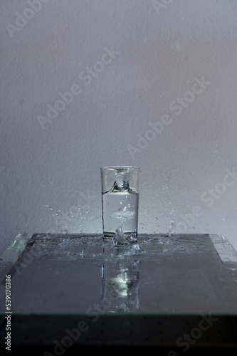 Throwing ice into a glass of water, splashing water.