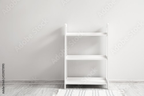 Tapeta Empty white shelving unit near light wall