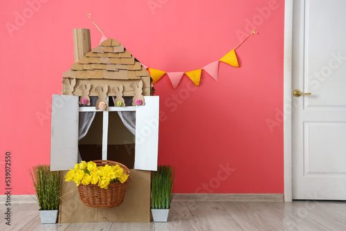 Toy cardboard house, flowers and plants in children's room