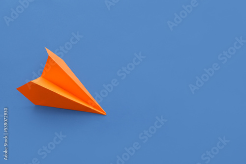 Orange paper plane on blue background